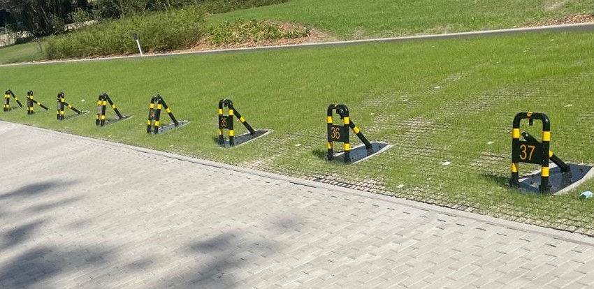 Bloakdy parkingowe zamontowane na podstawach na ekologicznym chłonącym wodę parkingu